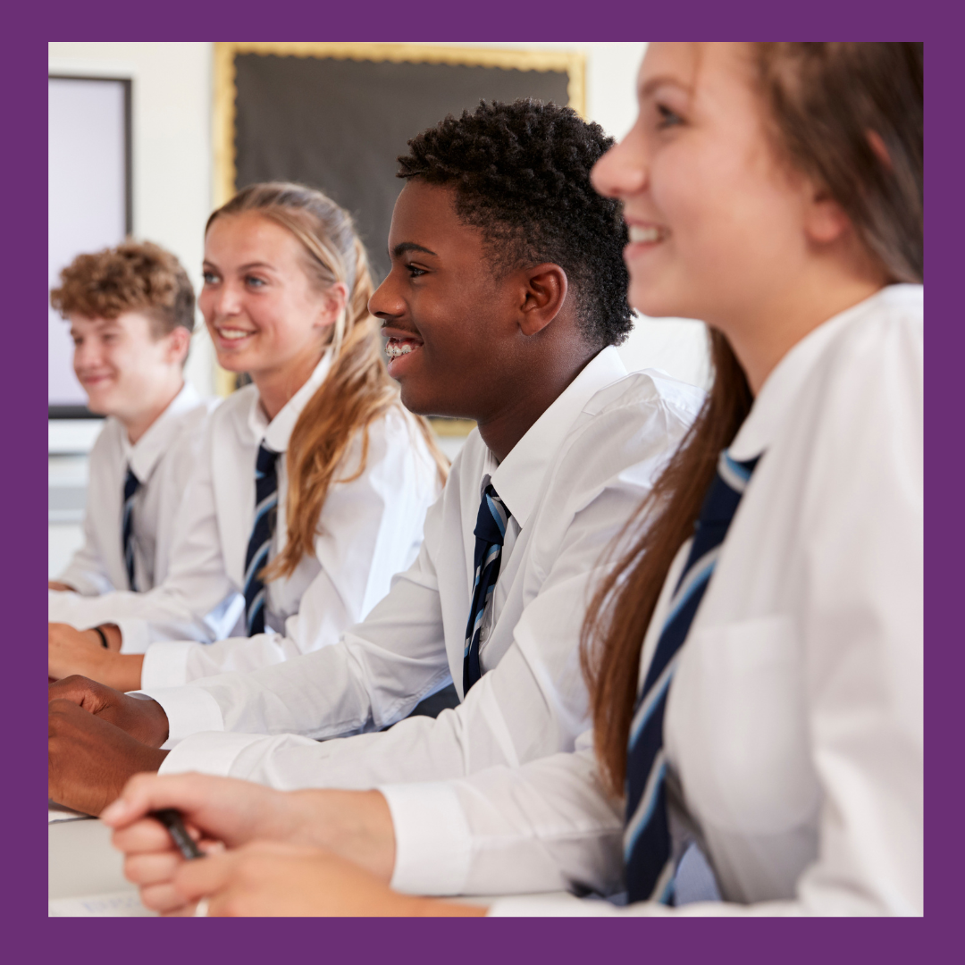 Secondary children smiling at desk